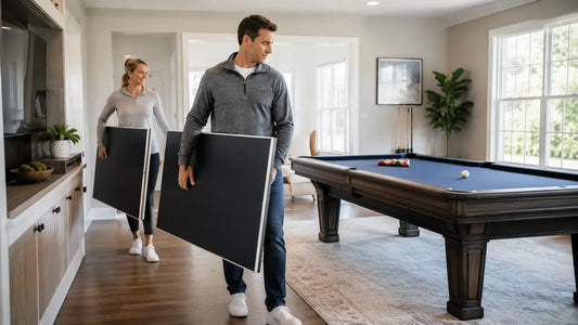 Two adults carrying folded ping pong conversion-top panels in a clean indoor game room beside a pool table.