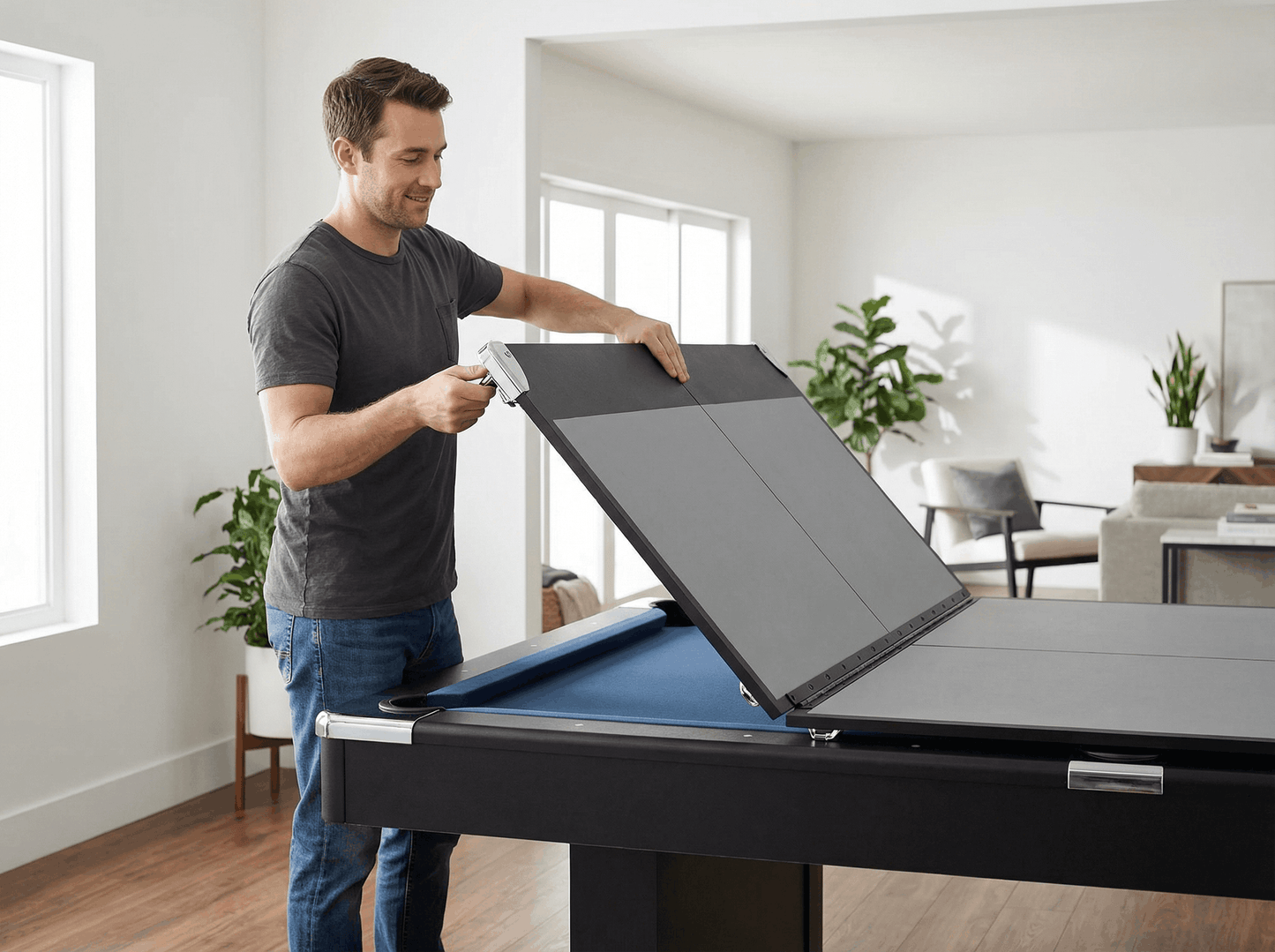 Man opening a pool table cover in a living room setting