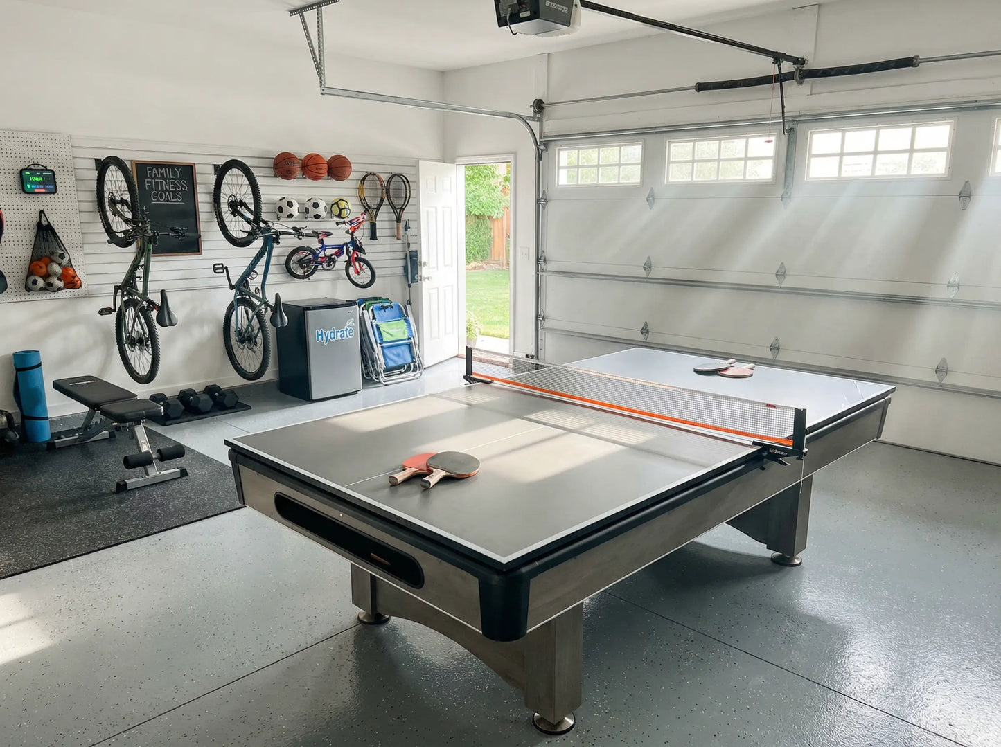Compact ping pong conversion top installed on a pool table in an organized garage game room