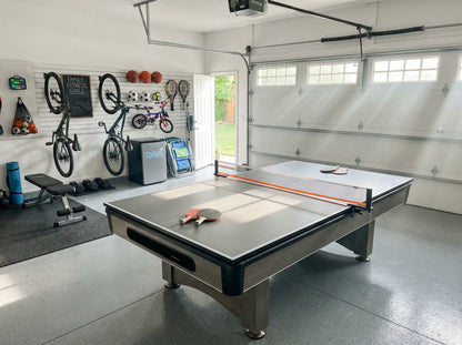 Compact ping pong conversion top installed on a pool table in an organized garage game room