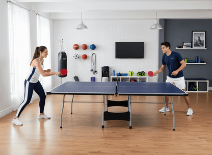 Two people playing ping pong in a living room with sports balls and equipment on the wall.