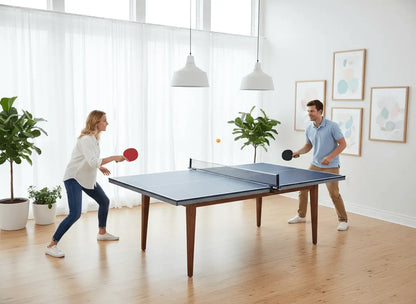 Two adults playing on a full-size ping pong conversion top in a bright living room