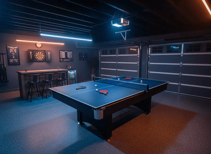 Blue ping pong conversion top installed on a pool table in an indoor garage game room