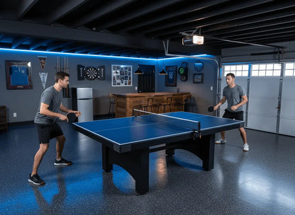 Two adults playing on a ping pong conversion top installed over a pool table in a garage