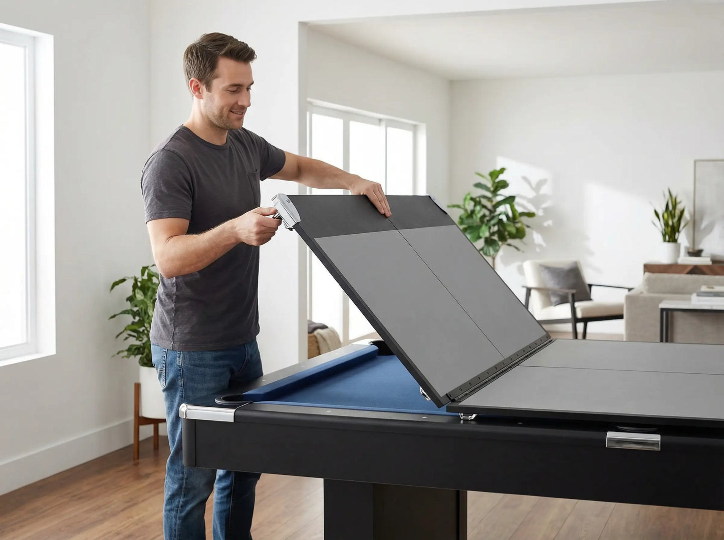 Adult carefully positioning a folded ping pong conversion-top half on a pool table